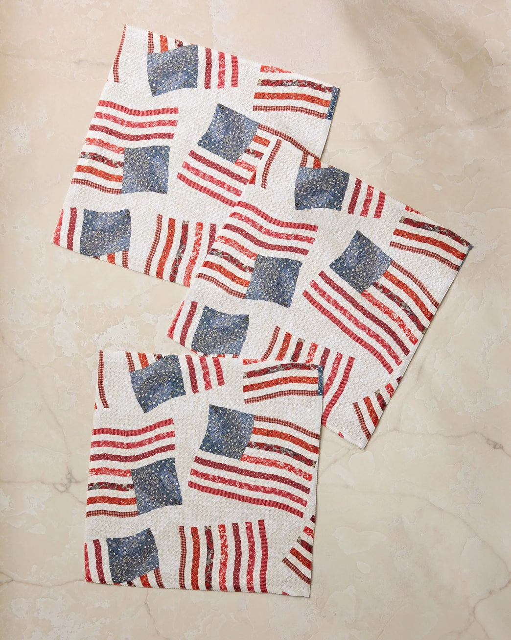 Set of three dish drying towels with red, white, and blue patchwork themed American flag pattern on a beige surface. Geometry House. 