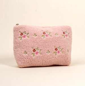 Light pink sherpa teddy cosmetics bag with embroidered red and pink flowers on the front. 