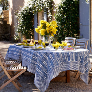 French inspired blue floral printed tablecloth with vibrant yellow blooms displayed across a outdoor dining table. 
