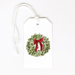 Gift tag with a Christmas wreath design featuring a red bow on a white background. Emily Lex Studios. 