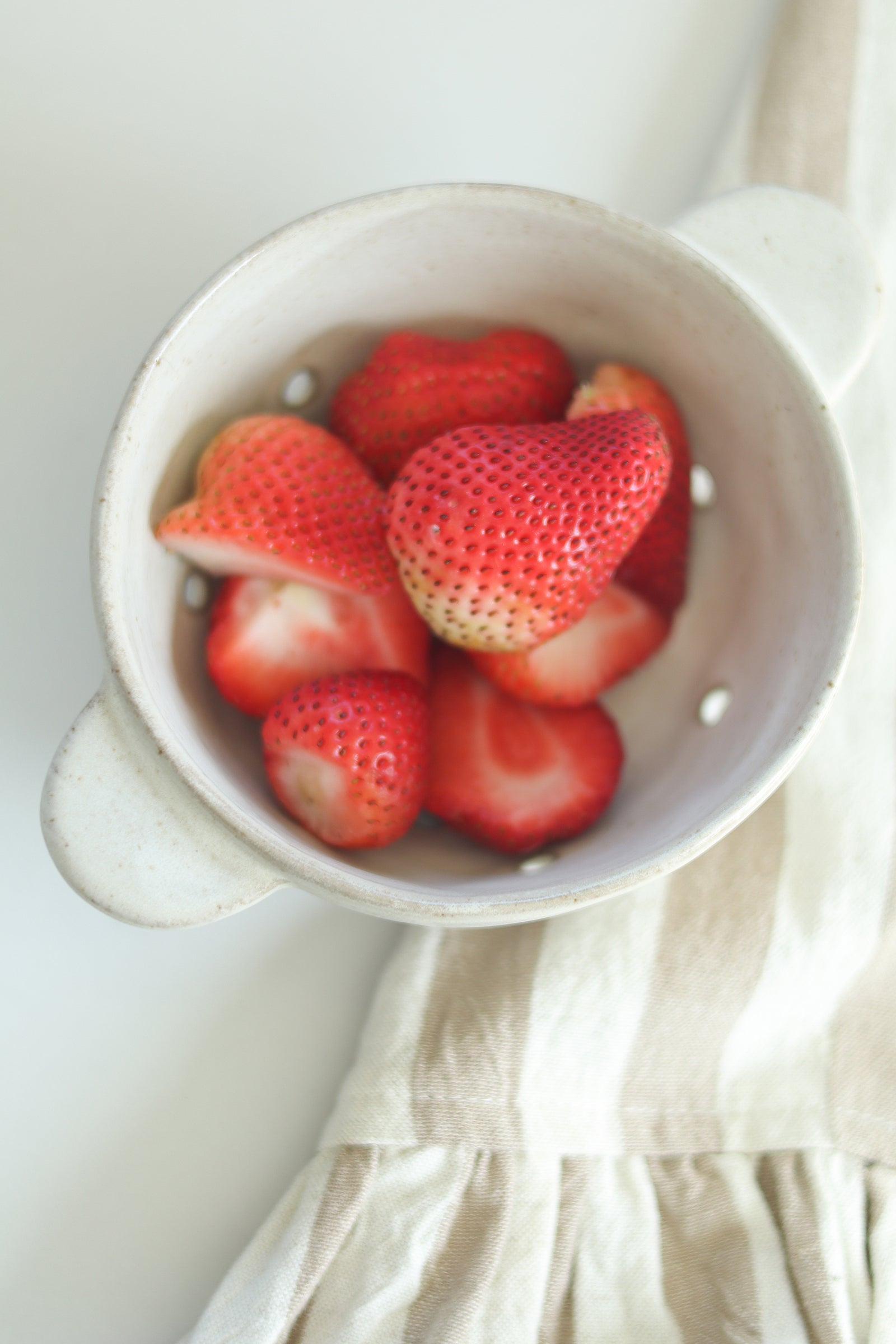 Organic style stoneware berry bowl with fresh strawberries displayed. 