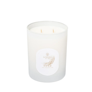 White candle labeled Sand on a white background. 