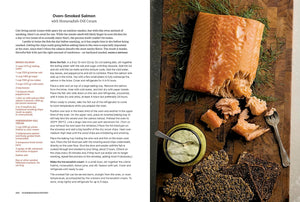 A printed recipe spread featuring text on the left titled 'Oven-Smoked Salmon with Horseradish & Cream' and a large photo on the right showing cooked salmon, cream, herbs, and utensils on a rustic wooden surface. "Scandinavian Everyday." 