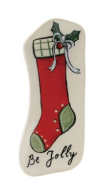 A Christmas stocking ornament featuring a red stocking with green accents, a white plaid cuff, holly, and the words 'Be Jolly' on a cream background.