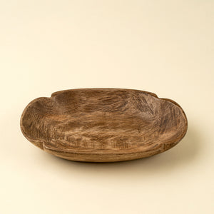 Wooden oval carved bowl on a beige background. 