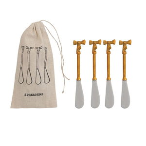 Set of four silver spreaders with brass bow handles accompanied by a linen drawstring bag labeled 'Spreaders' on a white background.