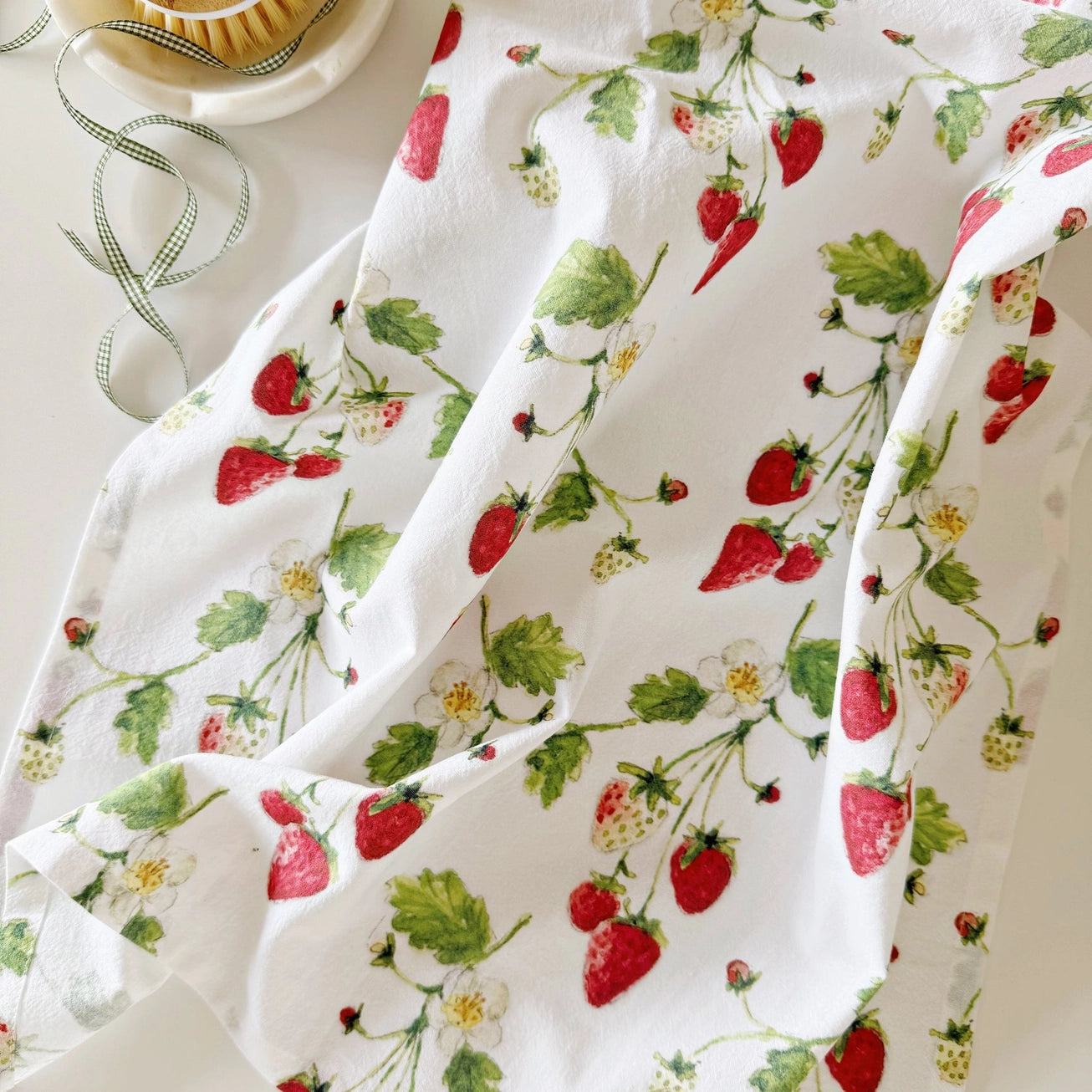 Cotton tea towel with strawberry watercolor pattern on a white background. Emily Lex Studios.