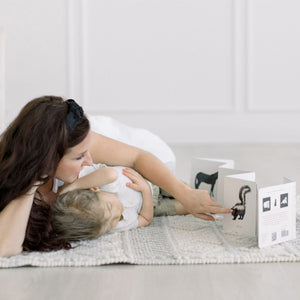 Woman and baby on floor enjoying tummy time while using the Tummy Time book set. Tabitha Paige. 