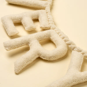 Cream-colored felt letter garland spelling "Very Merry", shown in a close-up shot against a matching cream background.