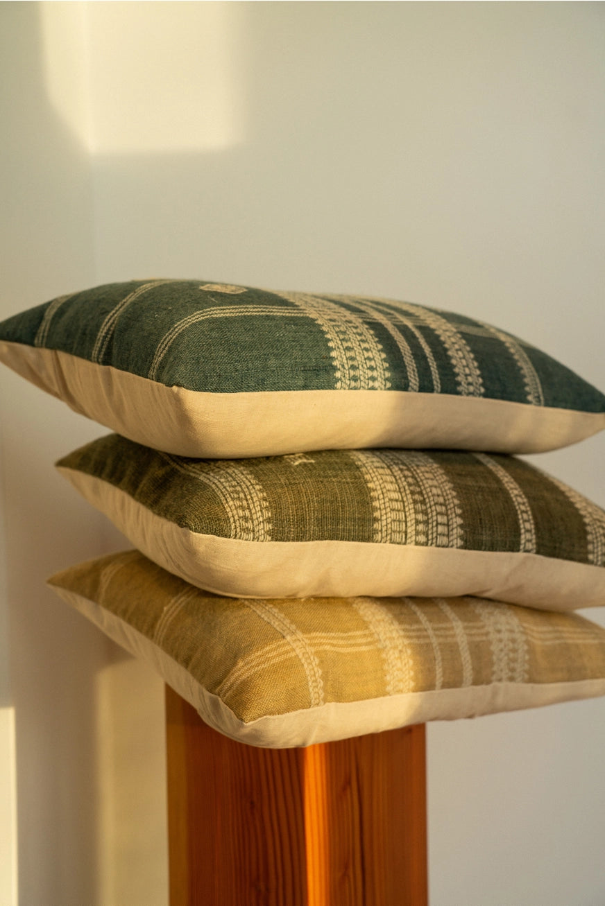 Stack of patterned pillows on a wooden stand against a white wall