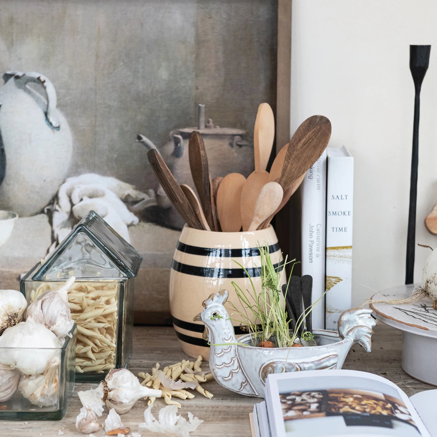 Vintage inspired black and cream striped crock vase displayed on counter with wooden kitchen utensils stored inside. 