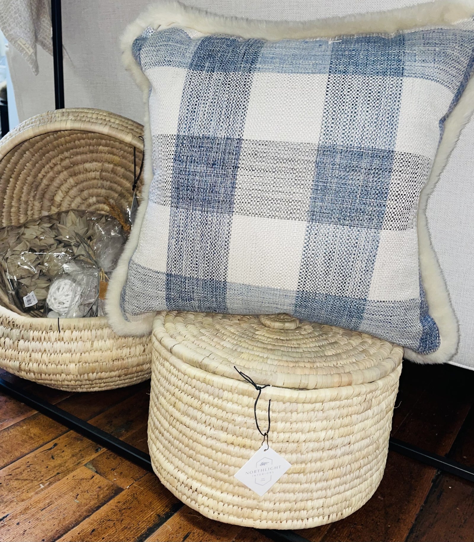 Rustic blue and white checkered buffalo print pillow on top of wicker basket. 