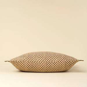 Decorative linen lumbar pillow with a block print check pattern on a beige background. Side profile view. 