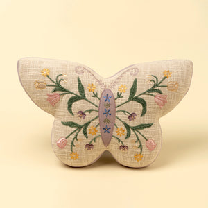 Butterfly-shaped pillow with floral embroidery on a beige background