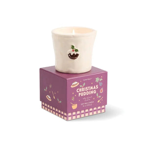 A white ceramic Christmas pudding candle by Paddywax sits on top of its purple illustrated packaging box against a white background.