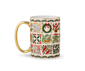 A ceramic mug with a gold handle and rim, decorated with a vintage-style Christmas grid pattern featuring holly, wreaths, birds, and mistletoe on an off-white background.