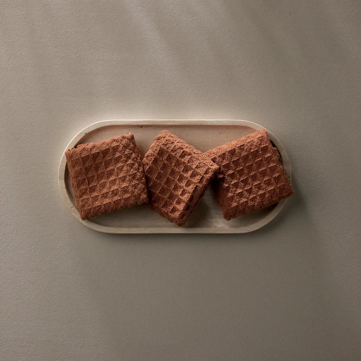 Three waffle washcloths on a rectangular plate against a gray background