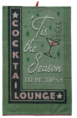 A green decorative towel with a holiday cocktail theme. The design features the text 'Tis the Season to be Tipsy' in white script, a martini glass illustration with a red cherry, green starburst accents, and a black vertical panel on the left reading 'COCKTAIL LOUNGE' in white and pink lettering.