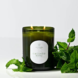 Green candle labeled 'Crushed Mint' by LINNEA with fresh mint leaves on a white background. 