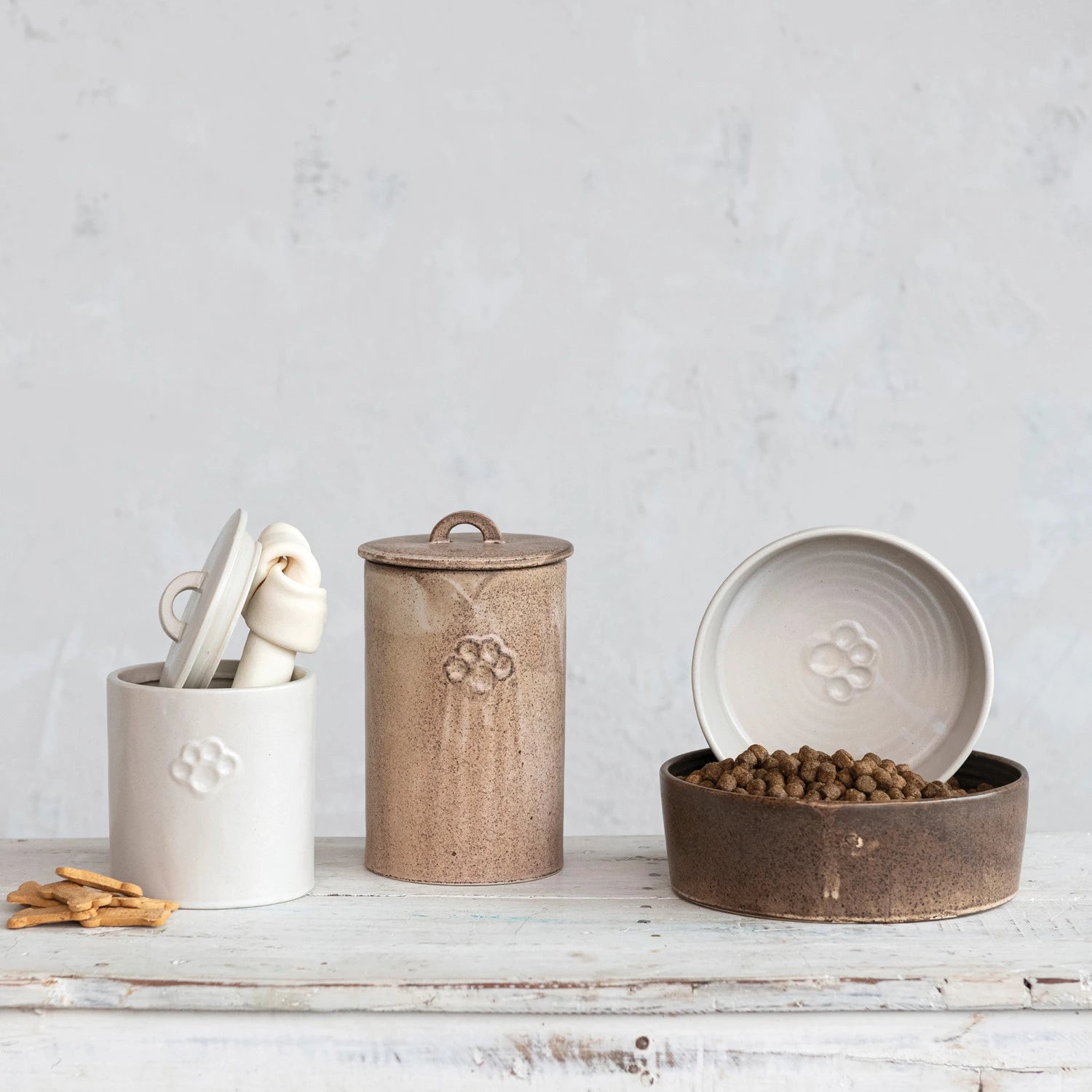 Collection of ceramic and metal dog canisters, including debossed paw print dog bowl. 