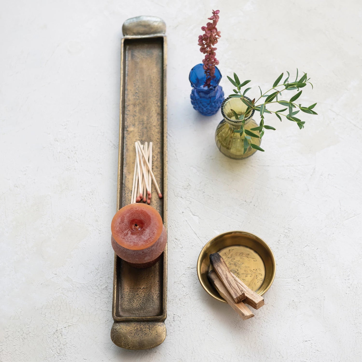 Cast aluminum antique brass tray with candle and matches displayed inside, resting on table next to bud vases. 