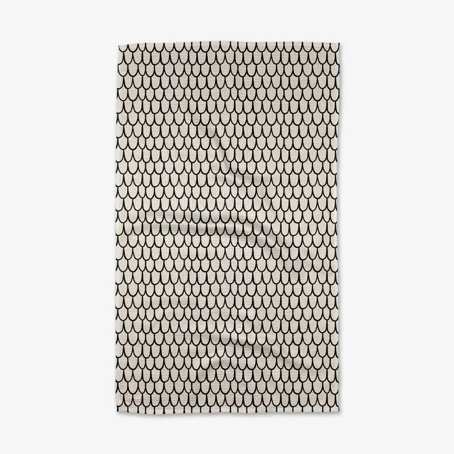 Patterned tea towel with black and white fish scale design on a plain background