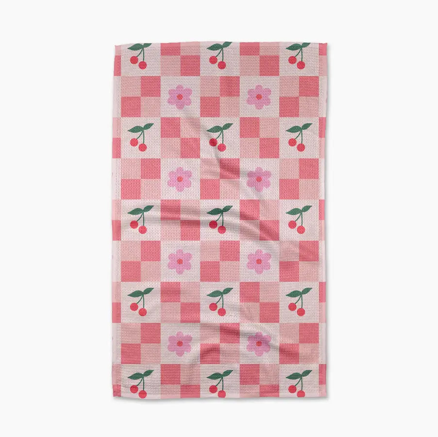 pink hued checked tea towel with pink flowers and cherries.