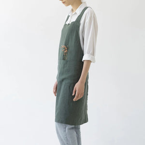 Person wearing a green linen apron on a white background