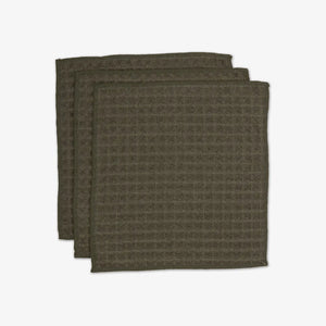 Three green textured washcloths on a white background