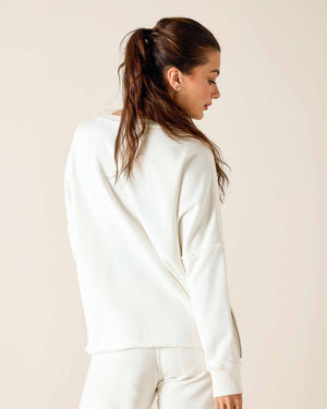 Woman wearing a white french terry and cotton crewneck sweatshirt against a beige background. Mersea. 