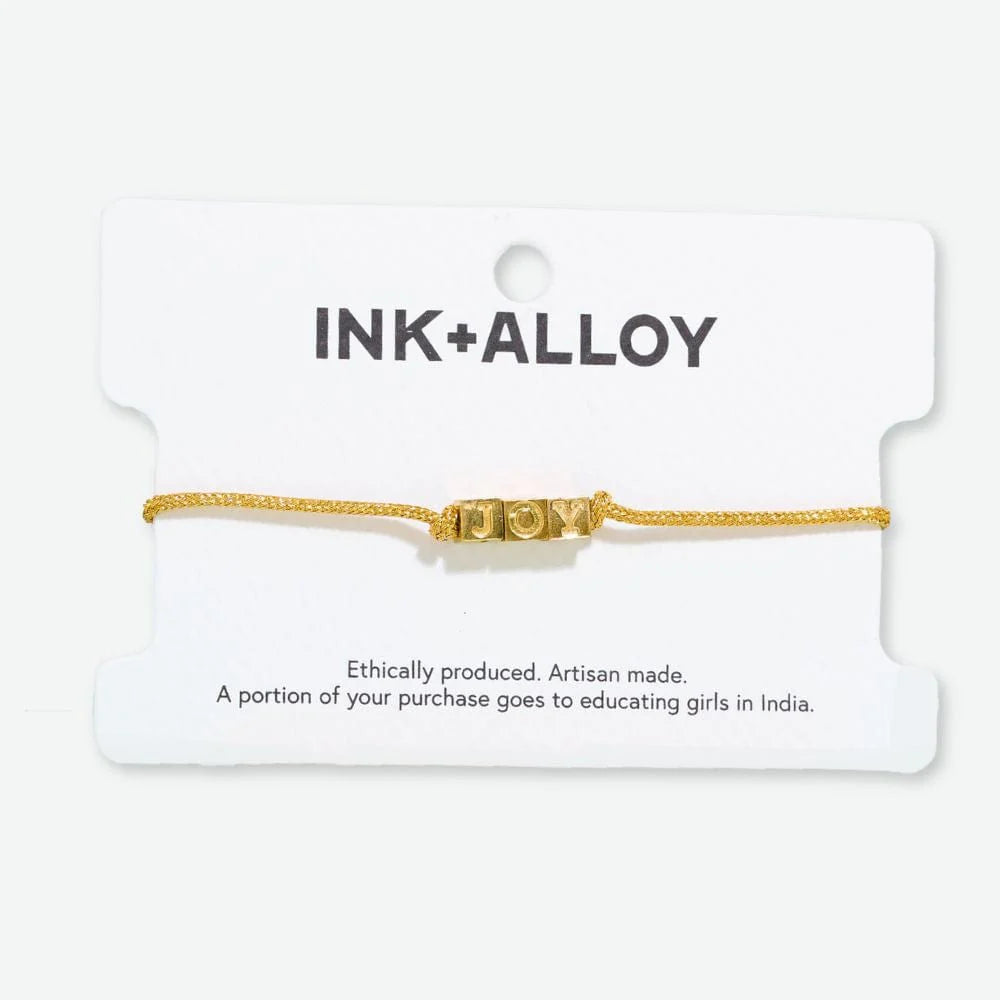 adjustable gold cord bracelet with word "joy" in brass. 