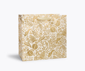 Large gold floral-fruit patterned gift bag on a white background. 