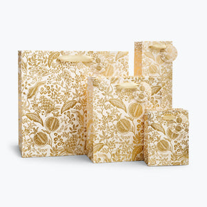 Set of gold floral-fruit patterned gift bags on a white background. 