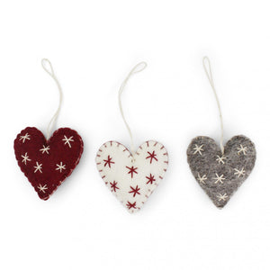 Three heart-shaped wool ornaments with star patterns against a white background.