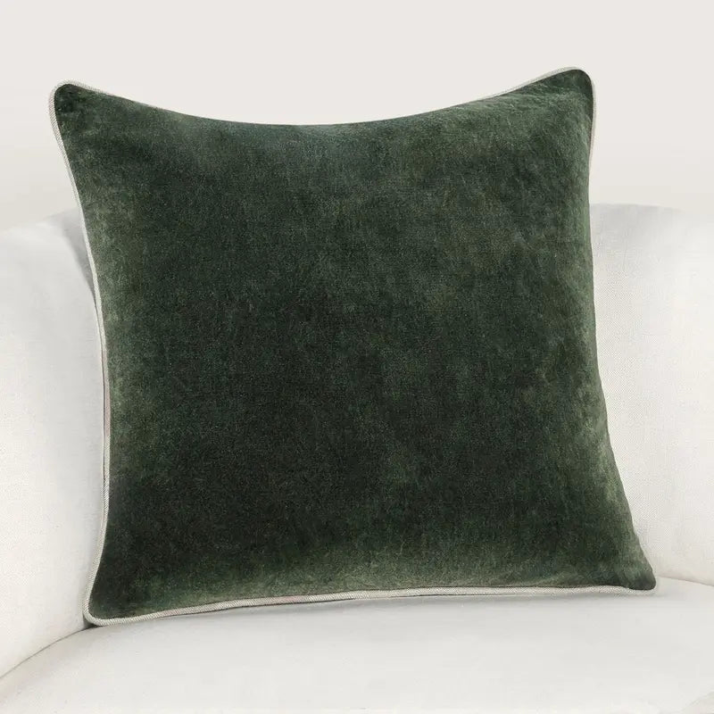 Forest green stonewashed heirloom velvet square pillow on a white sofa.