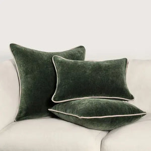 Forest green stonewashed heirloom velvet square pillow with two other sized pillows of the same fabric on a white sofa.