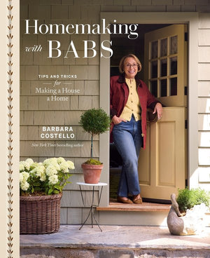Book cover for 'Homemaking with BABS' by Barbara Costello, showing a woman standing in a doorway on a house porch with the title text overlaid at the top.