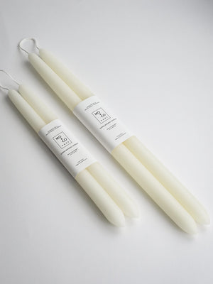 A set of 10 inch and 14 inch ivory beeswax taper candle against a white background. 
