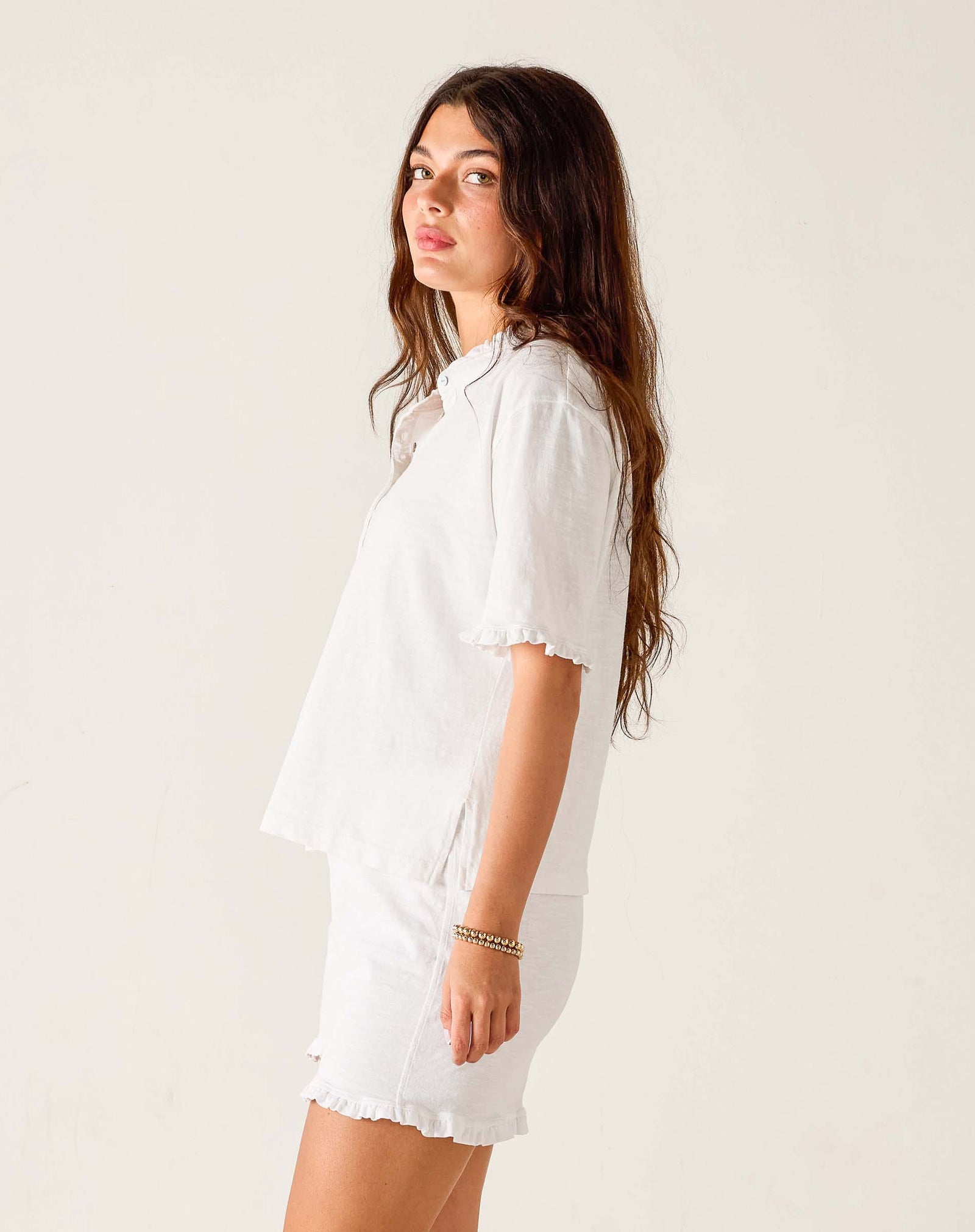 Woman wearing a white shirt and shorts on a plain background