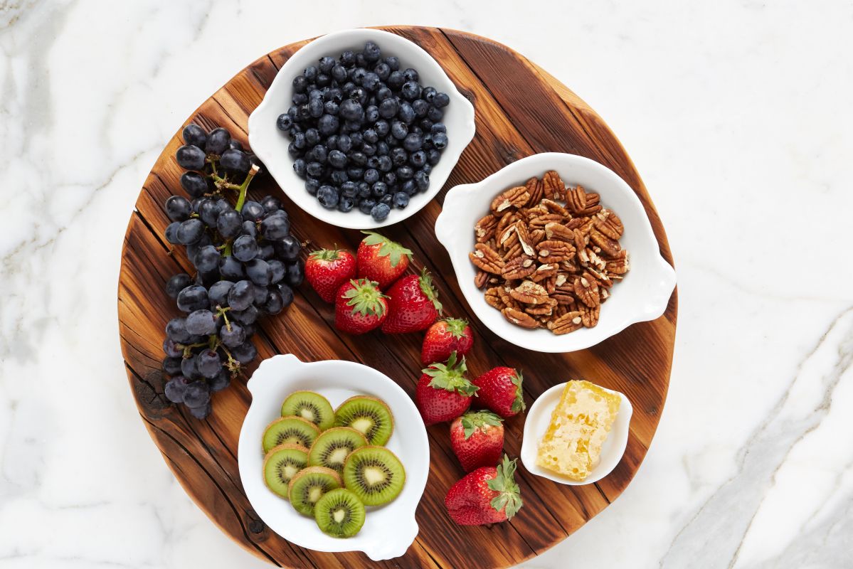 Large reclaimed wood trivet with charcuterie spread of fruits and nuts displayed