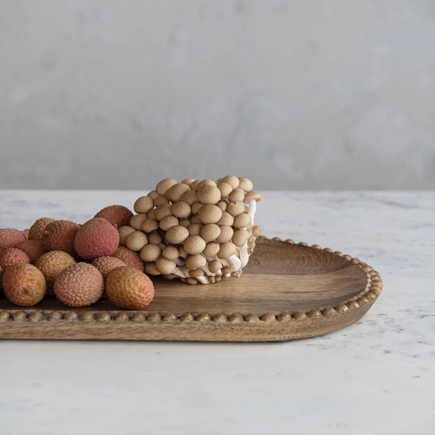 Gold beaded mango wood tray with berries and nuts displayed. 