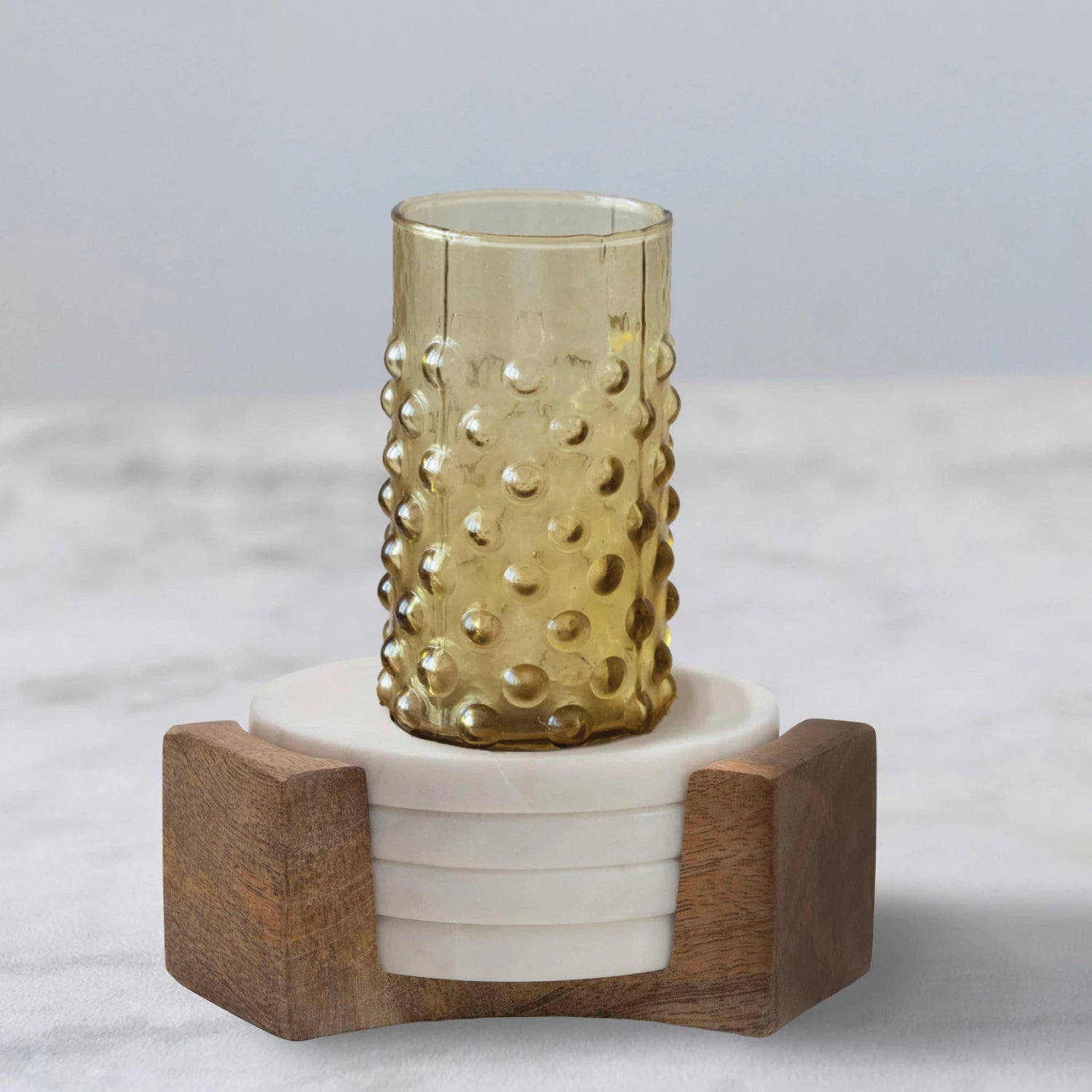 White marble coasters in a set of four with mango wood holder. Retro hobnail glass displayed on top. 