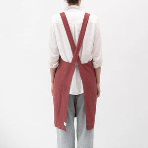 Person wearing a red linen apron over a white shirt on a white background