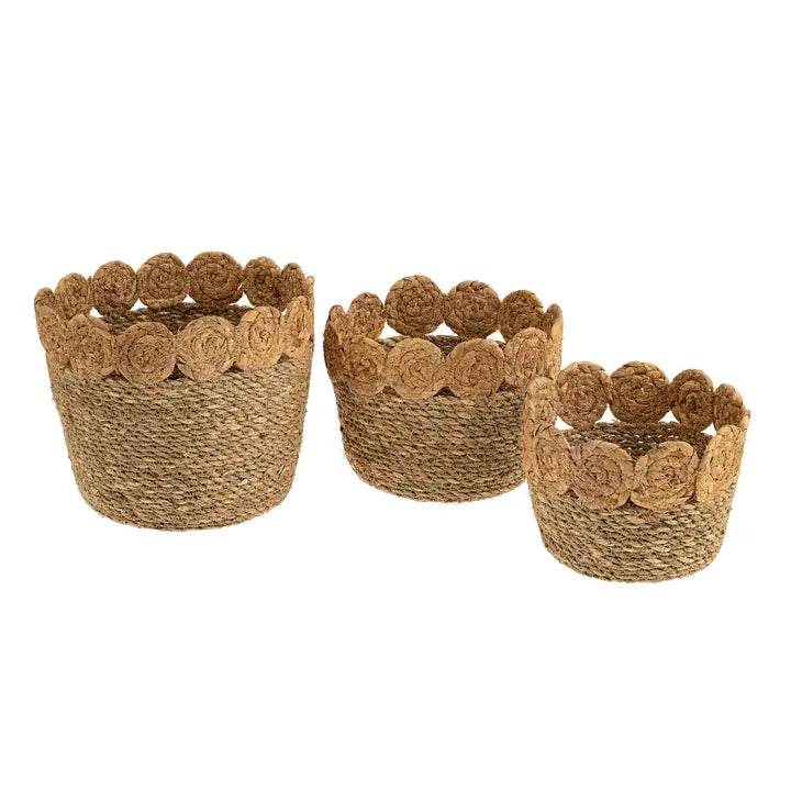 Three seagrass woven baskets with scalloped  top edges on a white background. 