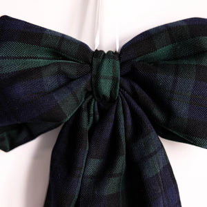 Close up view of fabric blue and green plaid holiday bow against a white background. 