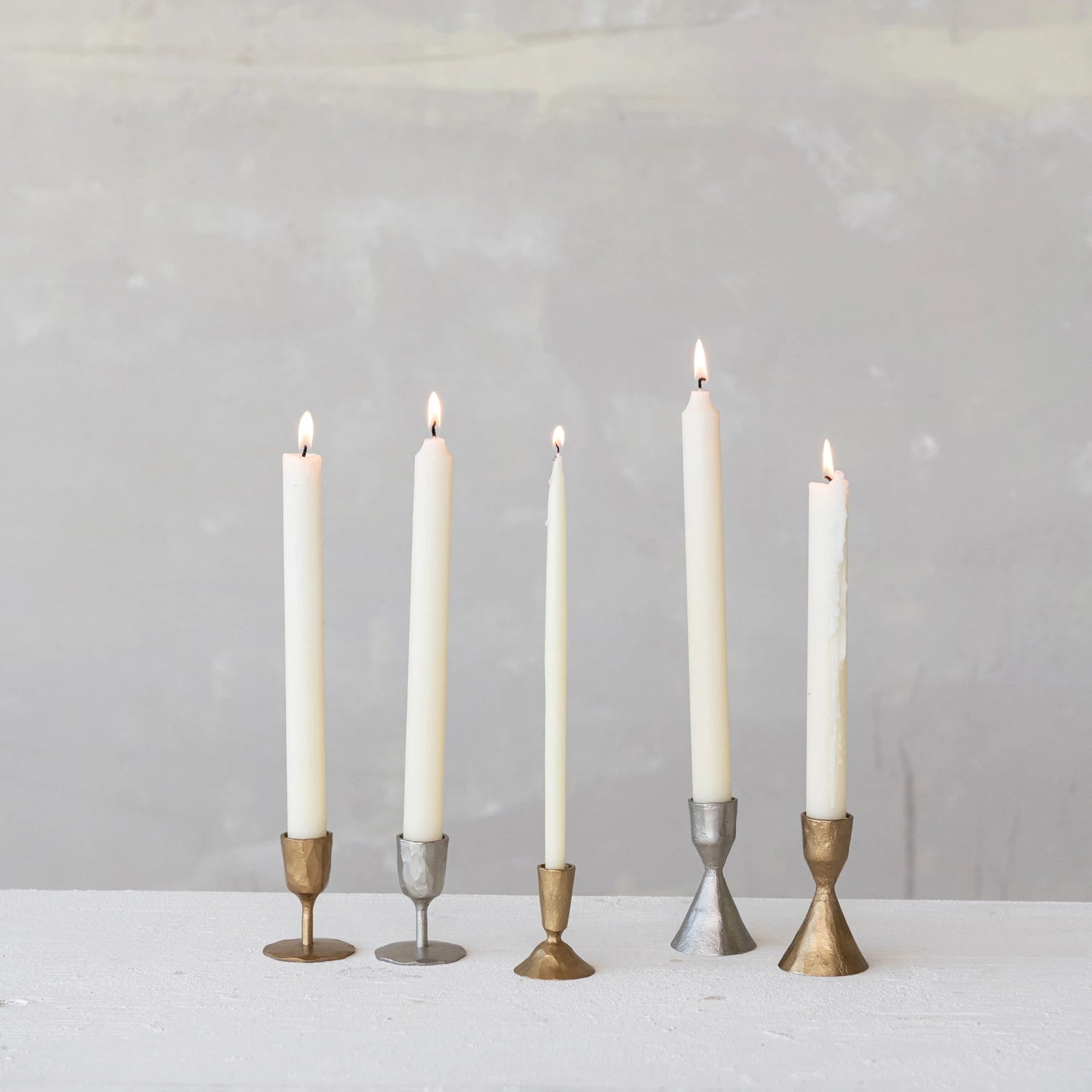 Collection of varying sized hand forged cast iron candle tapers in silver and gold. 
