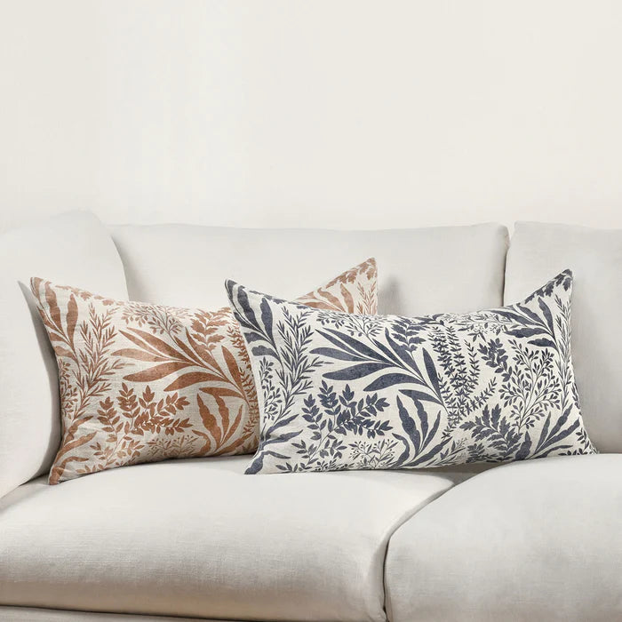 Floral pattern in denim blue and terracotta orange lumbar linen pillows on a white couch.
