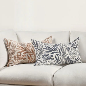 Floral pattern in denim blue and terracotta orange lumbar linen pillows on a white couch.