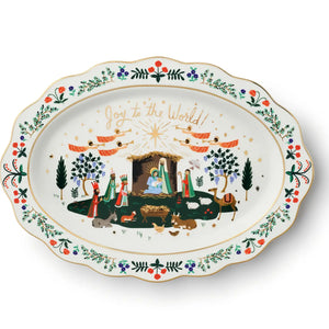 An oval white ceramic Christmas serving platter with a scalloped edge, decorated with a colorful nativity scene and the gold text 'Joy to the World!' on the rim.