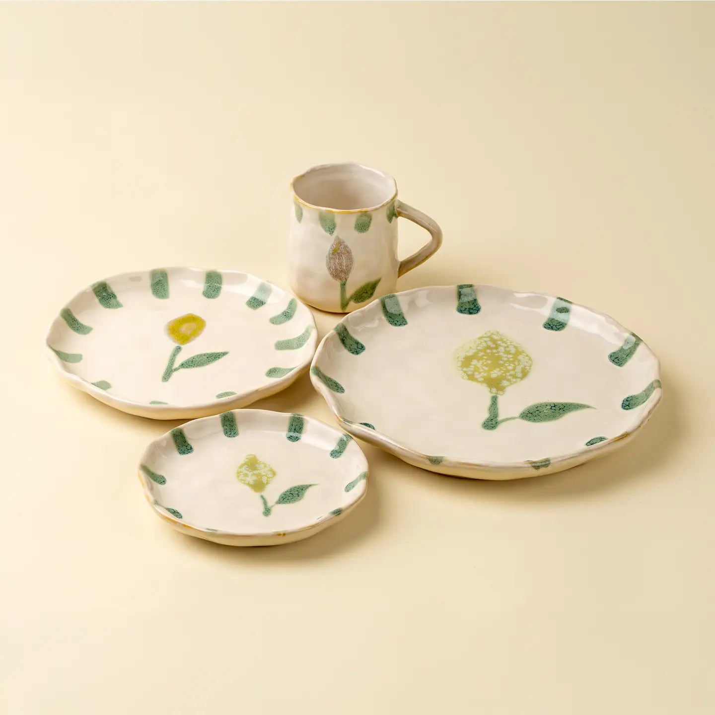 Stoneware tableware set with floral and lemon patterns on a beige background. Mug, dinner plate, salad plate, and appetizer plate. 